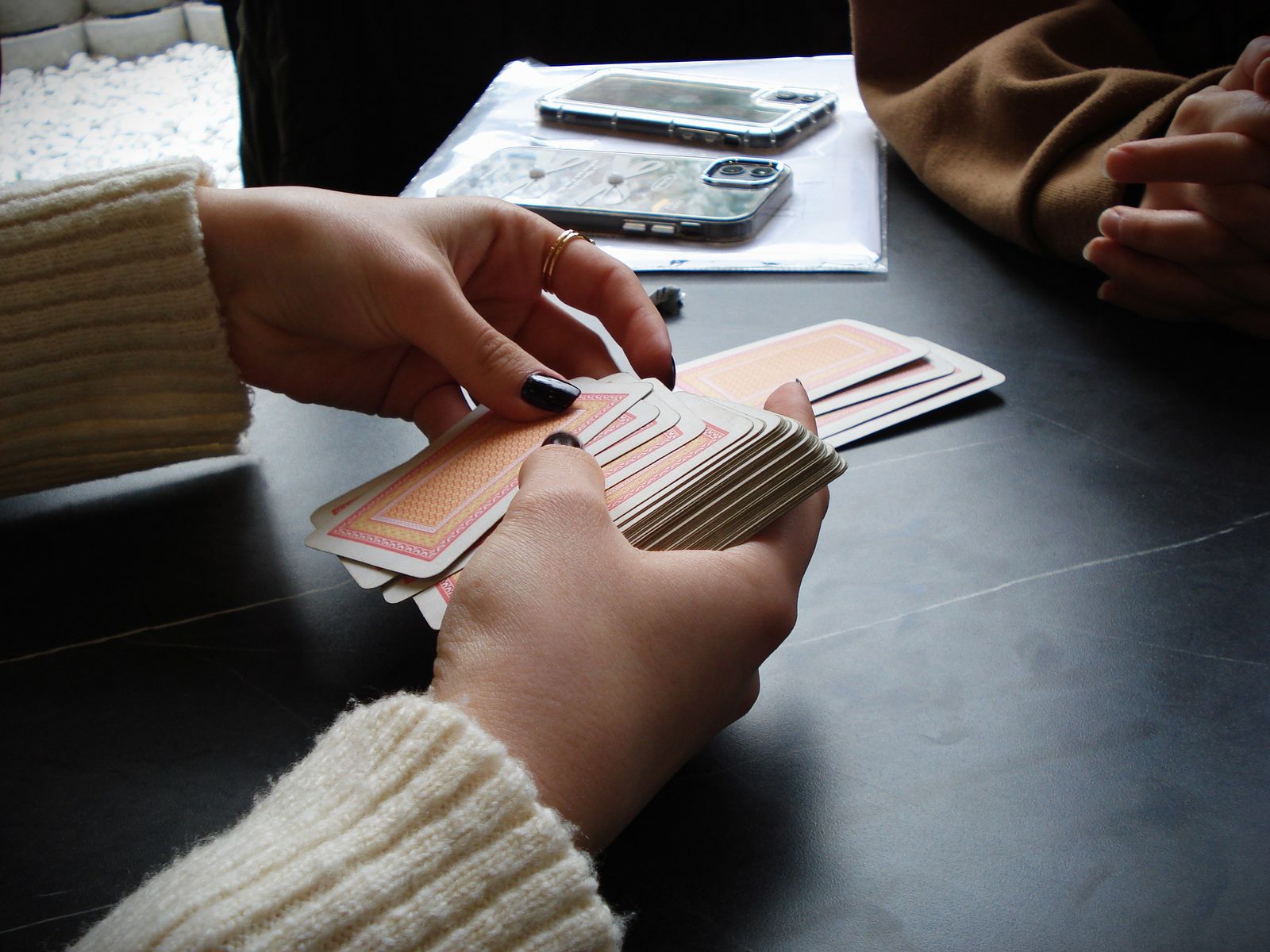 Hands holding standard playing cards at an indoor table